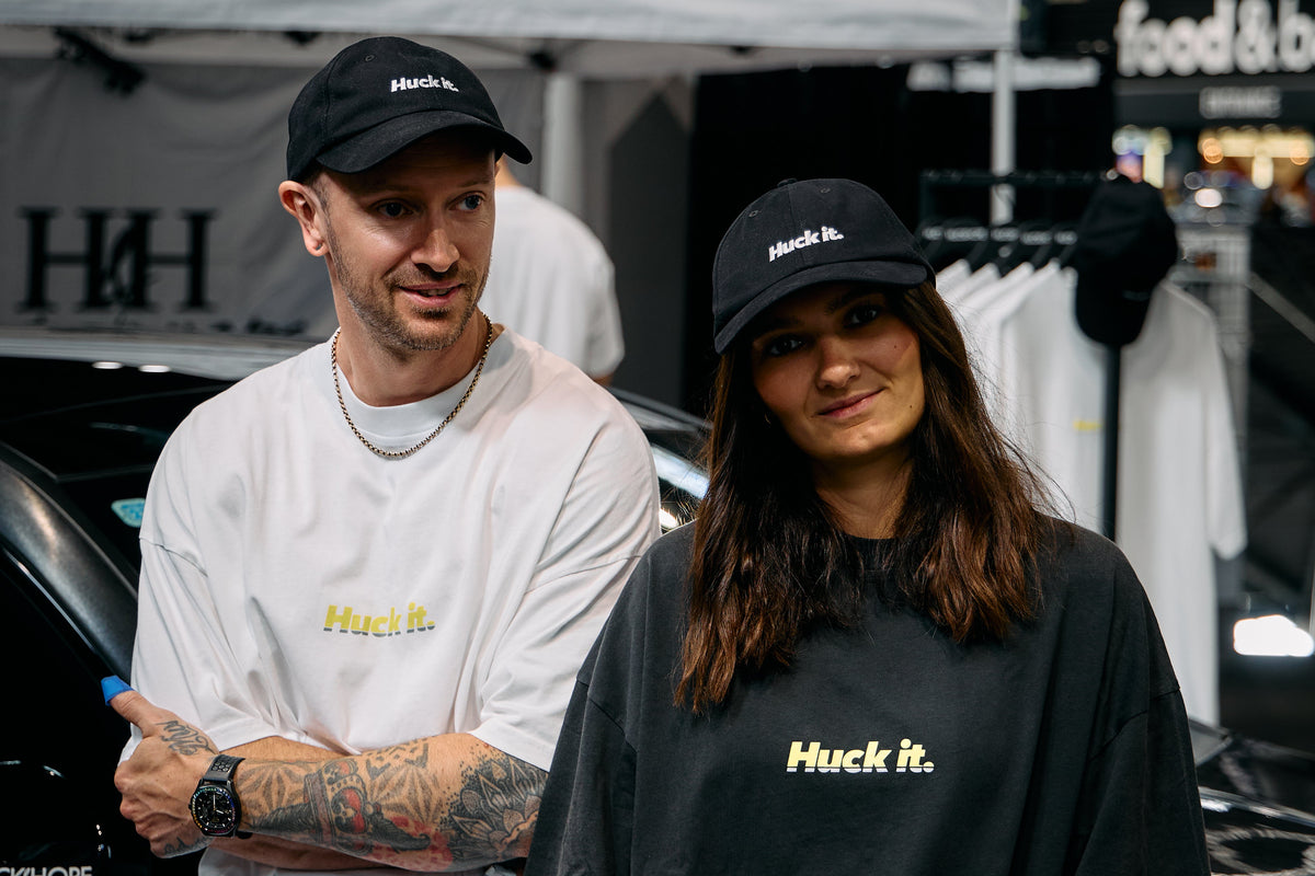 Two models wearing the Huck It mercedes tee, including a white t-shirt and black t-shirt with 'Huck it' written in yellow and grey .