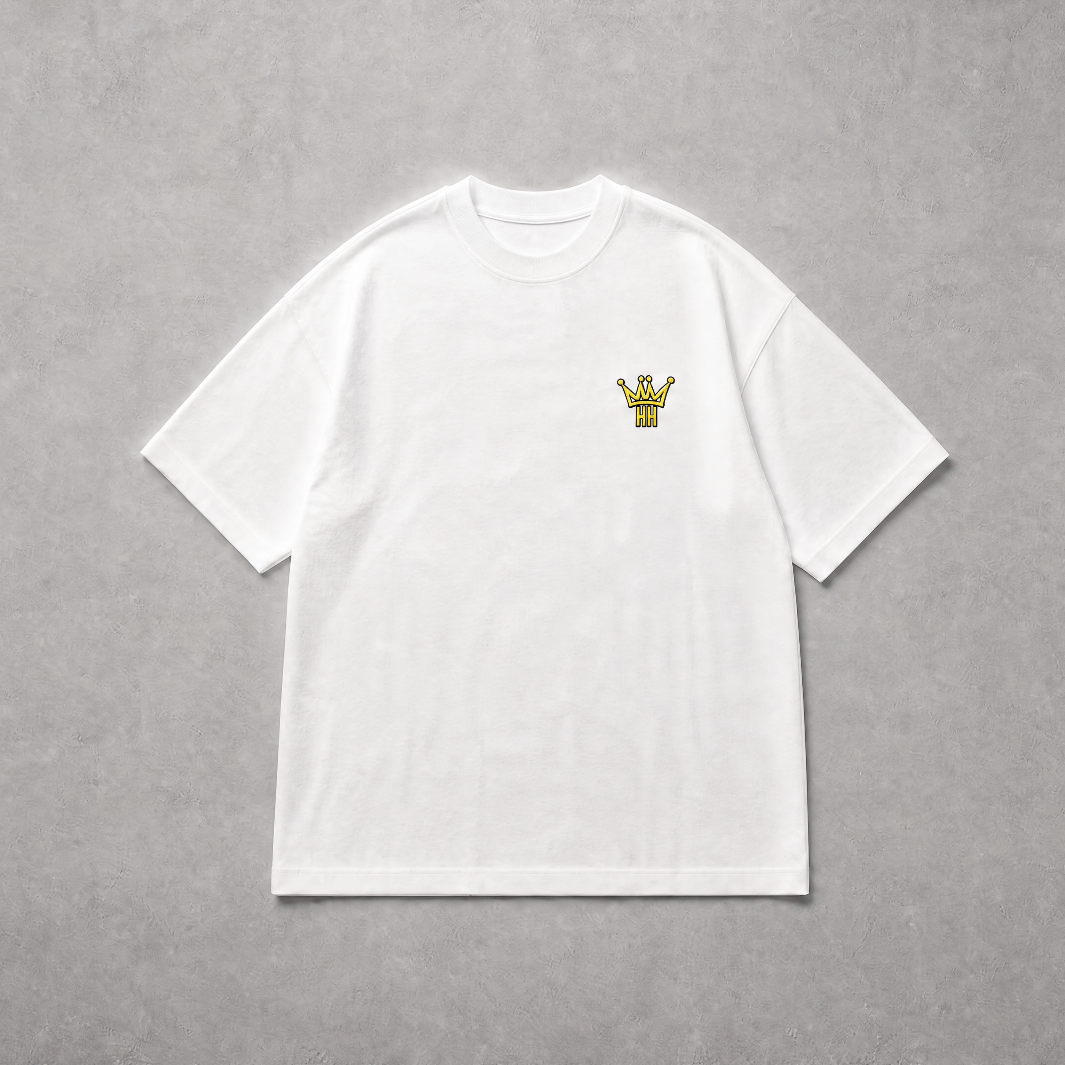A white short-sleeve crewneck t-shirt with a small yellow graphic on the left chest, laid flat on a textured gray background.
