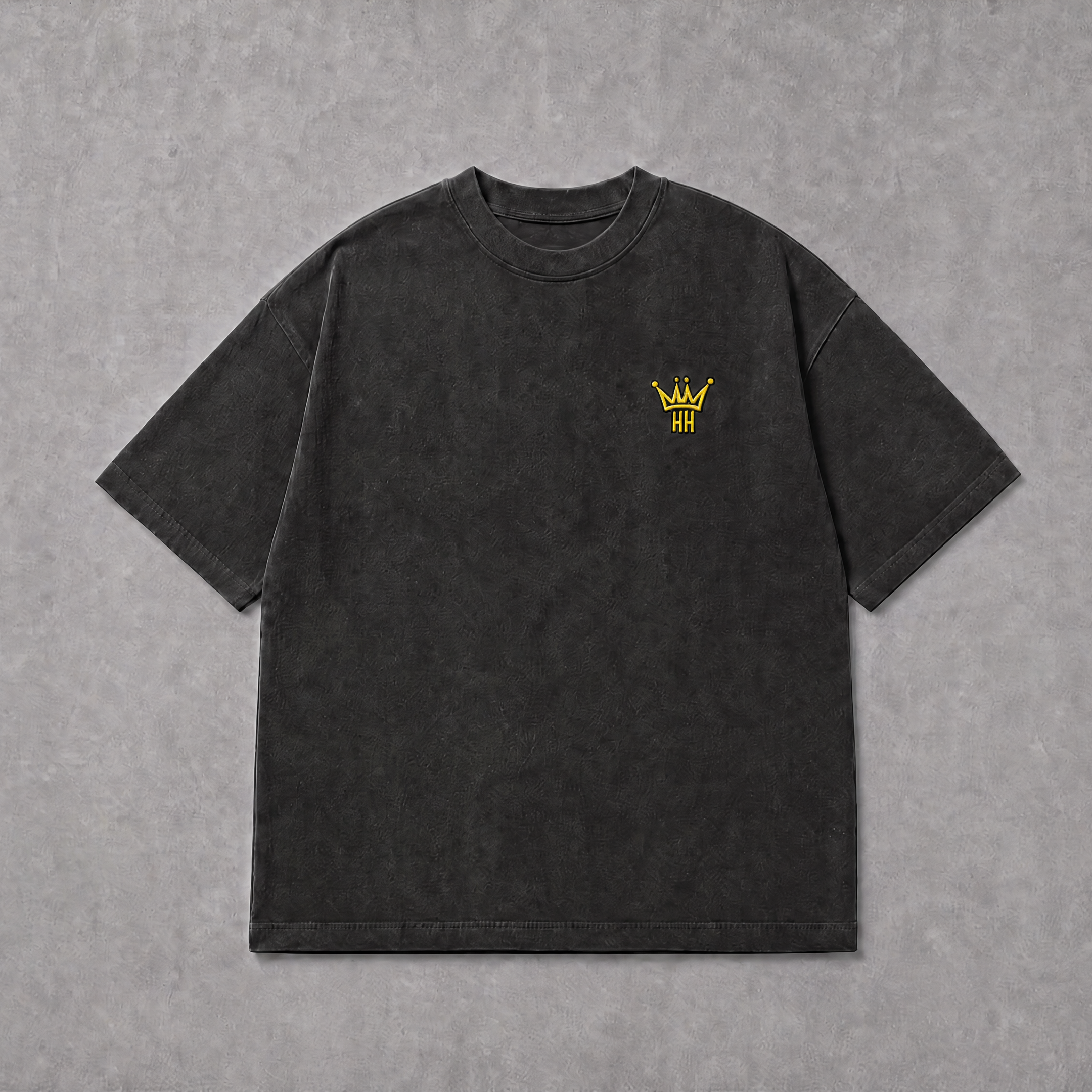 A dark charcoal gray short-sleeve t-shirt with a small yellow embroidered crown logo on the left chest, laid flat on a textured gray background.