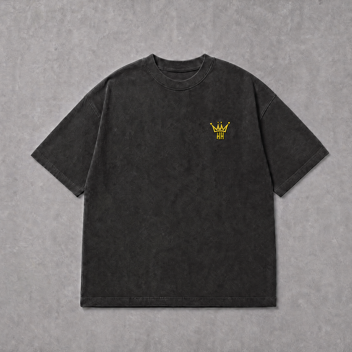 A dark charcoal gray short-sleeve t-shirt with a small yellow embroidered crown logo on the left chest, laid flat on a textured gray background.